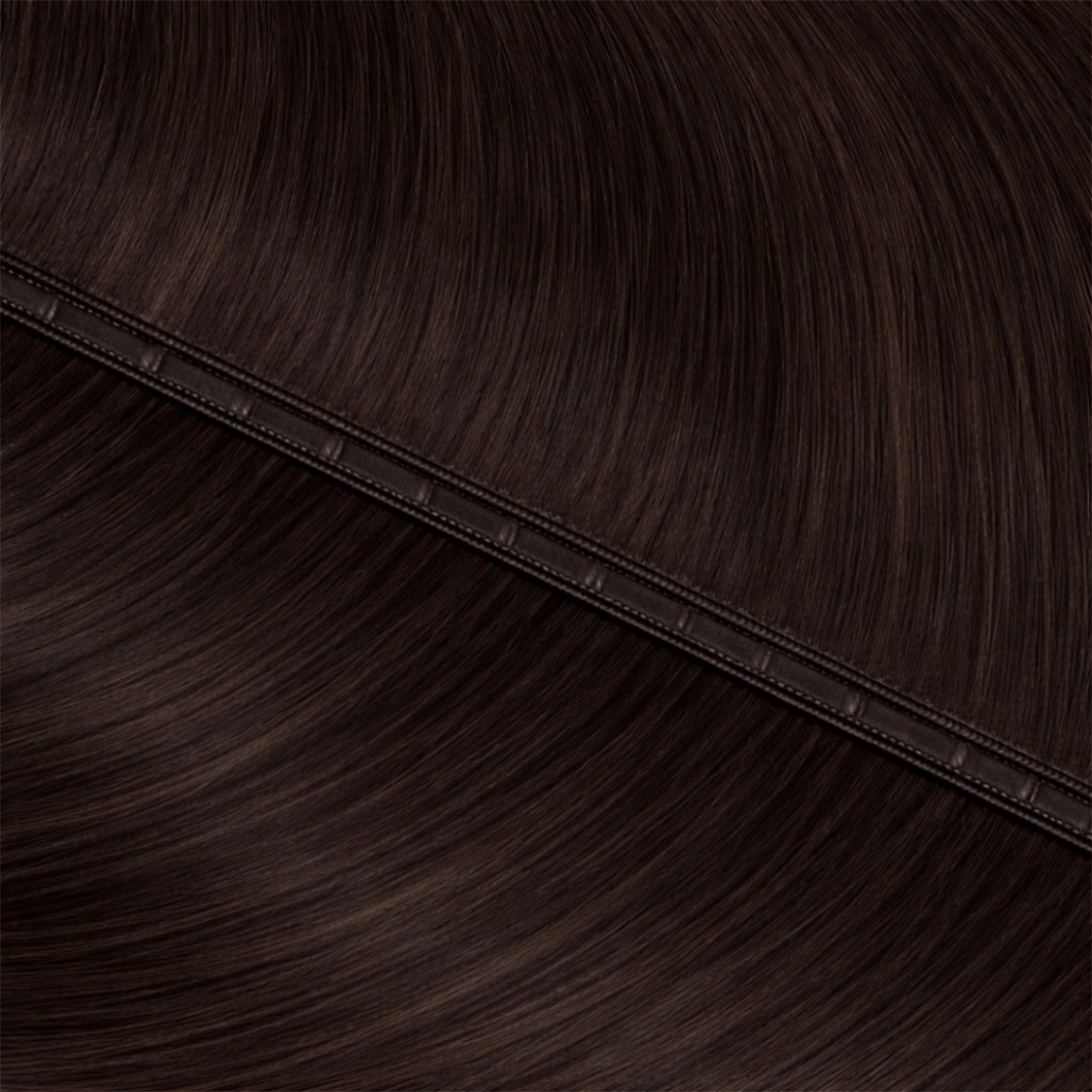 Close-up of dark brown hair extensions with a seam.